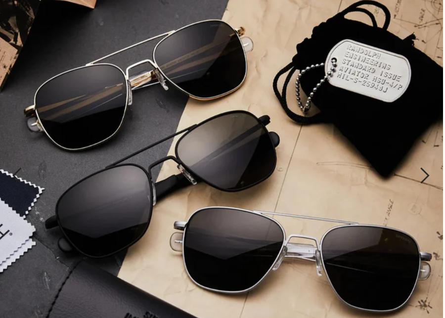 Three pairs of sunglasses on a textured surface with a black pouch.